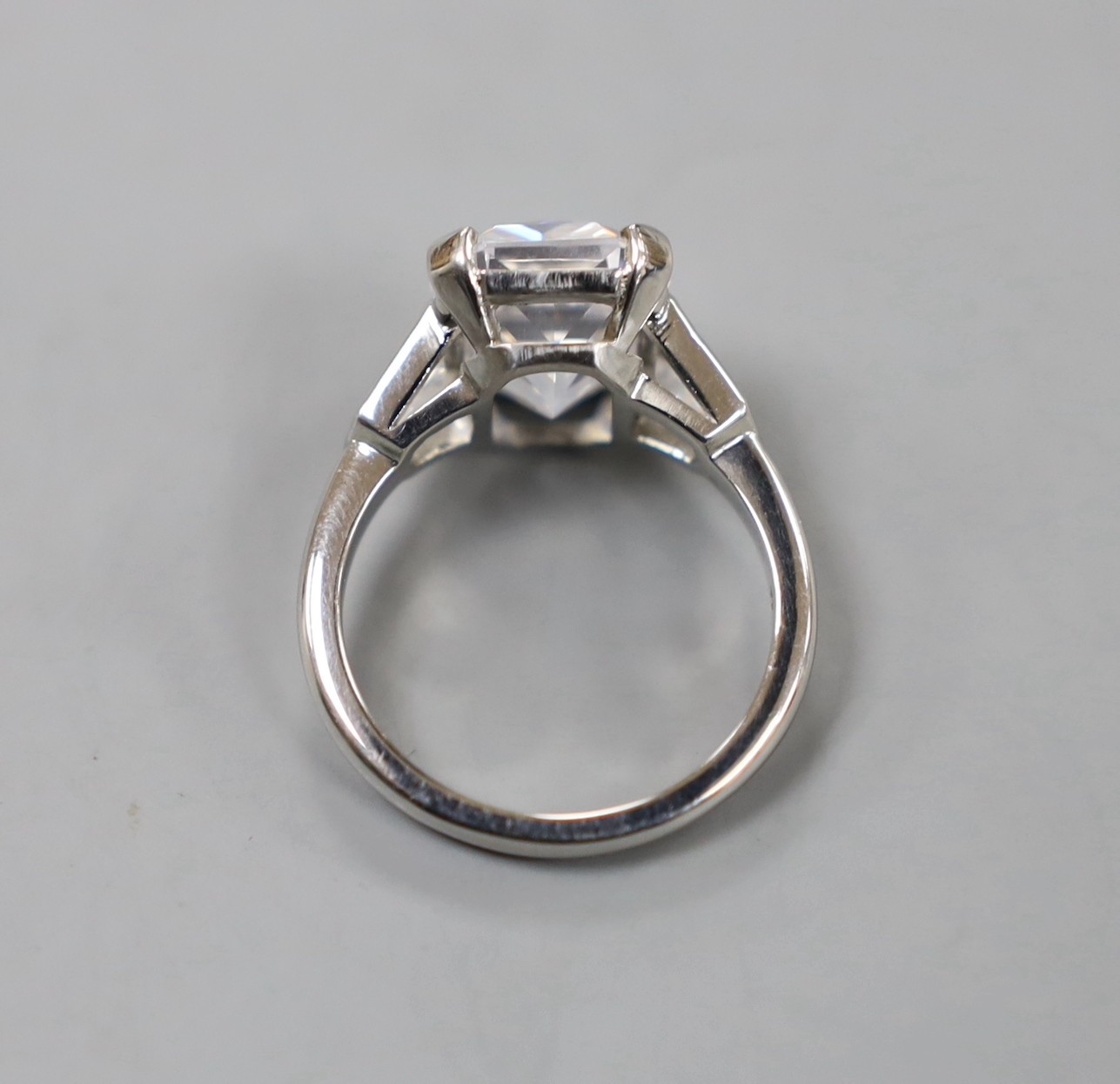 A white metal (stamped Plat) and fancy cut singe stone cubic zirconia set dress ring, with cubic zirconia set shoulders, size O, gross weight 9.7 grams.